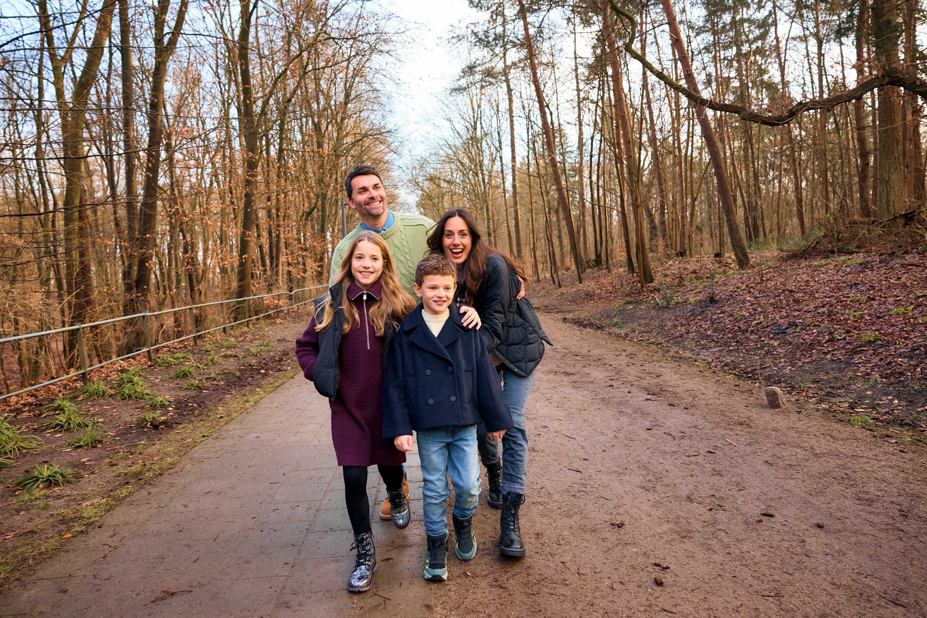 Familie bei Waldspaziergang mit Outdoor-Schuhen, Eltern und zwei Kinder im lässigen Look auf Waldweg, Herbst-Familie-Outfit